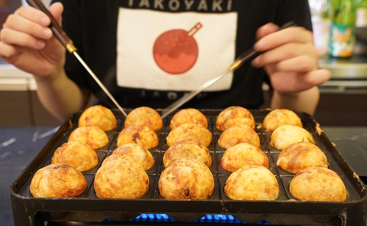 Cooking takoyaki on a hot takoyaki grill